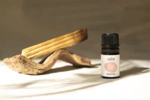 Olejek palo santo Oilo obok drewnianych szczap palo santo