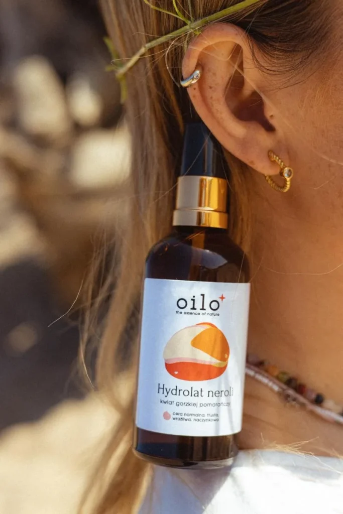 Hydrolat neroli 100 ml – butelka przy uchu kobiety, zbliżenie