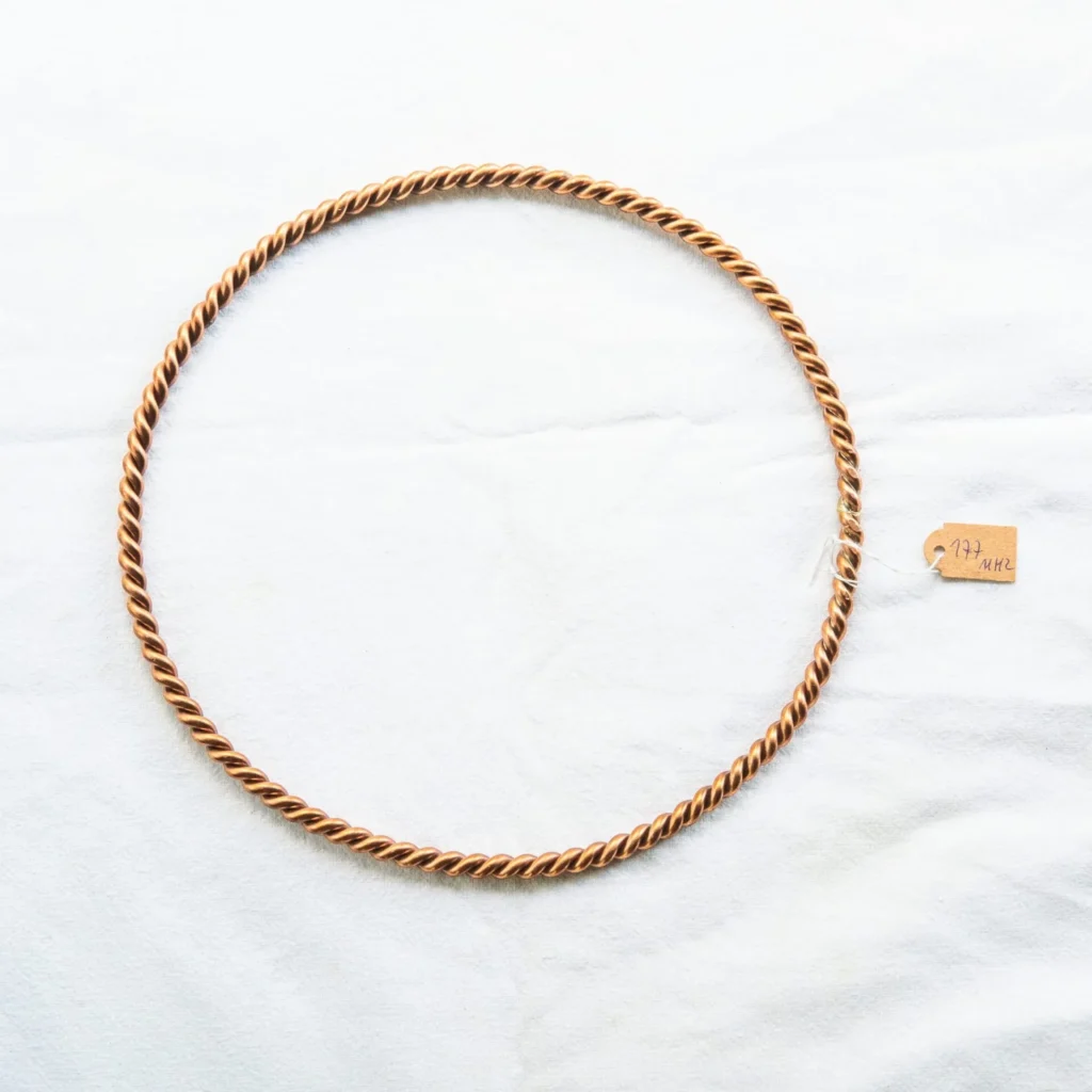 Pierścień tensorowy miedziany HANDMADE na białej tkaninie z metką rozmiaru