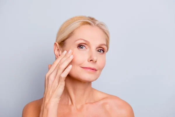 Kobieta dotykająca skóry twarzy – pielęgnacja anti-aging
